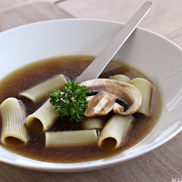 Tallerken med klar soppsuppe med pasta