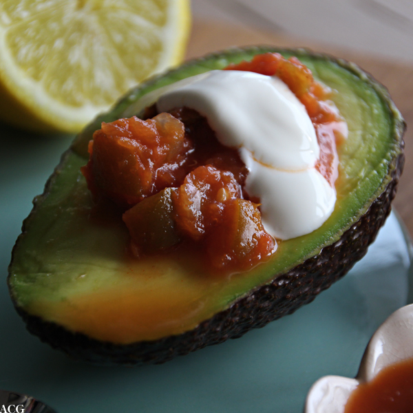 Nærbilde av halv avokado med salsa og rømme