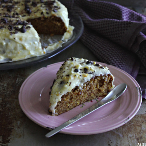 et stykke appelsinkake med hele kaken i bakgrunnen